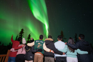 a group of people holding each other while watching the Northern Lights